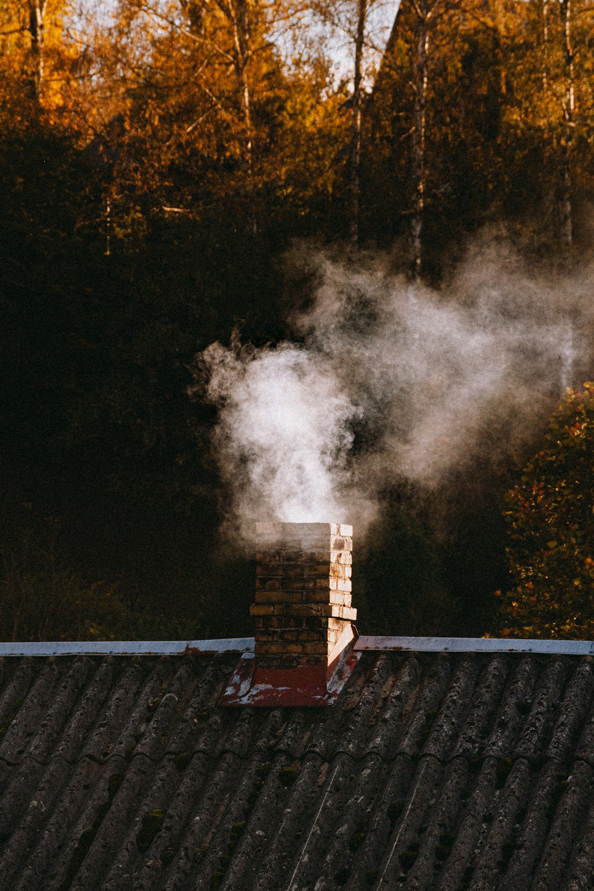 Brick chimney on roof with smoke rising - chimney cleaning Canterbury